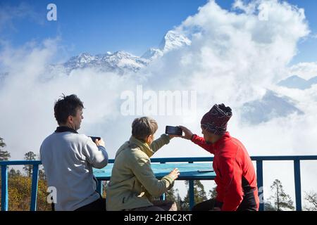 Trois voyageurs prennent des photos des sommets enneigés de l'Himalaya avec leur téléphone portable.Vue magnifique sur South Annapurna à Dobato, Népal 2021. Banque D'Images