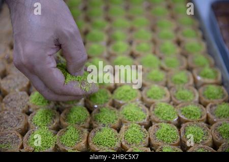 Images de la fabrication de pistachio baklava.Le chef prépare un dessert traditionnel Baklava.Le chef saupoudrer les arachides sur la baklava. Banque D'Images