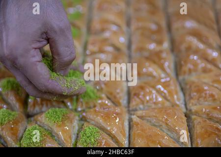 Images de la fabrication de pistachio baklava.Le chef prépare un dessert traditionnel Baklava.Le chef saupoudrer les arachides sur la baklava. Banque D'Images