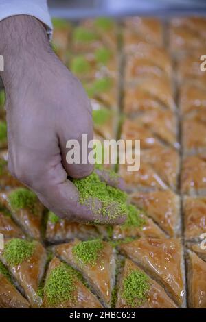 Images de la fabrication de pistachio baklava.Le chef prépare un dessert traditionnel Baklava.Le chef saupoudrer les arachides sur la baklava. Banque D'Images