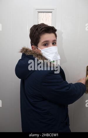 Un garçon scolaire qui rentrait à la maison avec un masque facial demande de se protéger contre les virus Banque D'Images