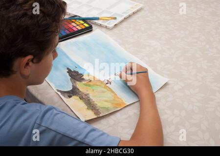 Un garçon peint une photo d'un phare aux aquarelles, prise le 13 août 2020 Banque D'Images