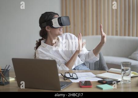 Une femme heureuse explorant le monde augmentée au travail, touchant 3D objets virtuels avec les mains Banque D'Images