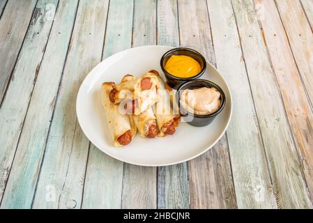 saucisses enrobées de tortilla de maïs avec fromage et sauces à trempette Banque D'Images