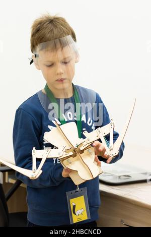 Garçon portant un écran de protection avec une maquette en bois mobile d'un squelette d'oiseau lors d'un événement scientifique pour enfants pendant la pandémie du coronavirus Banque D'Images