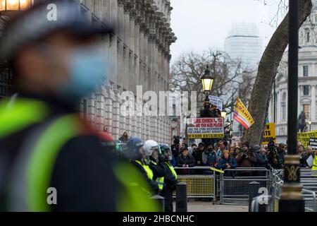 Londres, Royaume-Uni.18th décembre 2021.Un protestant tient un écriteau qui dit «Boris Johnson F. vous et vos politiques nazies.Emprisonner le gouvernement menteur pour crimes contre l'humanité.» pendant la manifestation.Suite à l'annonce du Premier ministre britannique Boris Johnson sur la mise en œuvre de passes à vide et du Plan C, qui mettra en place des blocages partiels, les anti-vaxxers s'évertue à Downing Street en fureur.Les manifestants se sont affrontés avec la police.Crédit : SOPA Images Limited/Alamy Live News Banque D'Images