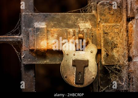 Gros plan d'un cadenas sur une porte en métal avec des toiles d'araignée Banque D'Images