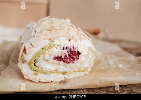 Section de meringue, rouleau de pistache sur parchemin.Texture du gâteau meringue avec framboises et pistaches à l'intérieur Banque D'Images