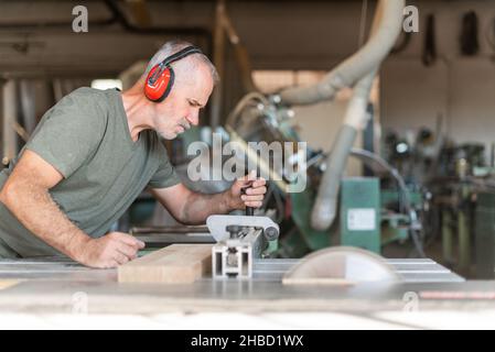Travailleur coupant du bois avec précision sur une scie à table coulissante Banque D'Images