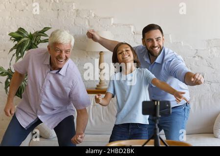 Une famille heureuse de trois générations enregistrant une danse amusante sur un téléphone portable. Banque D'Images