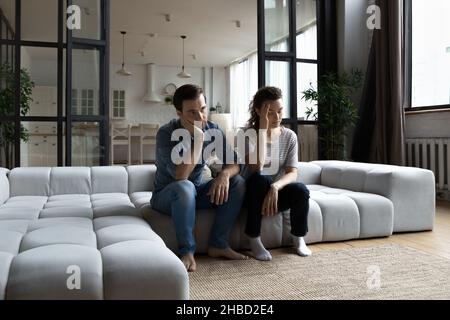 Jeune couple fatigué assis sur un canapé, pensant aux problèmes de relation Banque D'Images