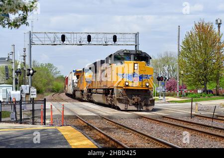 Winfield, Illinois, États-Unis.Deux locomotives dirigent un train de marchandises Union Pacific à travers une courbe et un passage à niveau protégé par des signaux de passage à niveau. Banque D'Images