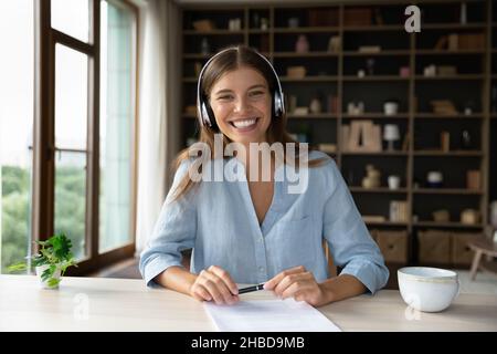 Souriante attrayante paisible jeune femme écoutant de la musique dans des écouteurs. Banque D'Images