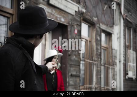 ISTANBUL, TURQUIE - 27 janvier 2020 : un homme dans un chapeau noir donnant une rose rouge à une femme dans une rue d'Istanbul Banque D'Images