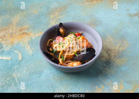 Pâtes italiennes aux moules crevettes, tomates cerises et fromage dans une assiette grise Banque D'Images