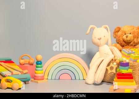 Arrière-plan des jouets.Boîte à jouets avec ours en peluche, lapin et hochet en bois.Jouets éducatifs en bois Montessori sur fond bleu pastel.Collection de jouets mignons Banque D'Images