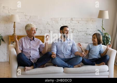 Bonne famille multigénérationnelle faisant des exercices de yoga à la maison. Banque D'Images