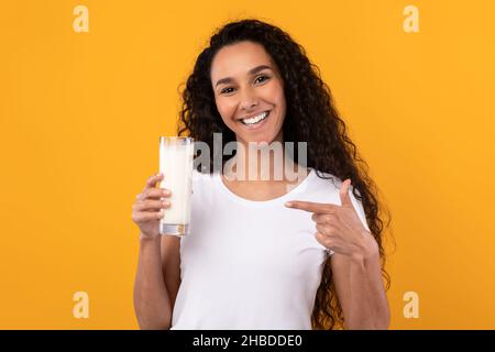 Bonne jeune femme pointant vers un verre de lait au Studio Banque D'Images