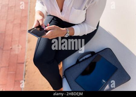 vue de dessus d'une femme d'affaires non reconnaissable tapant sur son téléphone en étant assise dans la ville, concept d'entrepreneur numérique et de style de vie urbain Banque D'Images