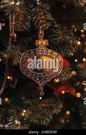 Jouet de Noël doré avec joie de texte accroché sur l'arbre de Noël.Guirlande de bokeh doré illuminée sur fond de fête en hiver Banque D'Images