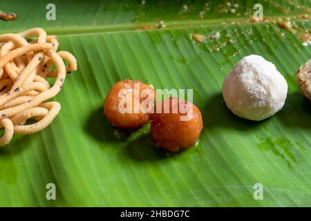 Gros plan sur le Gulab Jamun, un sucré indien, sur la feuille de banane, tout en mangeant des plats traditionnels servis sur la feuille de banane le jour de fête indien. Banque D'Images