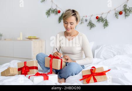 Bonne dame célébrant Noël écrire carte de voeux Banque D'Images
