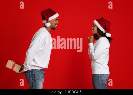 Un homme noir aimant tenant un cadeau de Noël pour sa petite amie excitée Banque D'Images