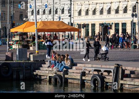 Groupe de jeunes femmes ou adolescents assis sur le quai de Kolera-allas par Kauppatori ou la place du marché à Helsinki, en Finlande Banque D'Images