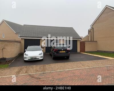 Voiture électrique et point de chargeur à l'extérieur d'une maison à Northampton Royaume-Uni en face des garages tesla voiture blanc point de charge blanc véhicule Drive allée Banque D'Images