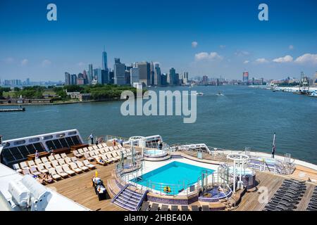 Vue de l'autre côté de la piscine arrière du paquebot Queen Mary 2 de Cunard, donnant sur le fleuve Hudson jusqu'aux gratte-ciel de New York Banque D'Images