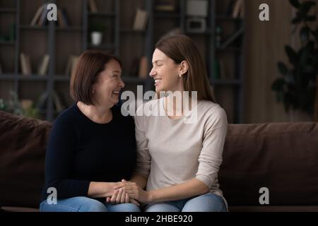 Fille adulte mère retraité s'asseoir sur le canapé tenir les mains parler Banque D'Images