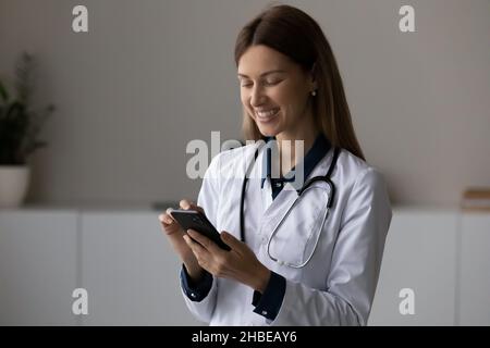 Jeune femme souriante médecin tenir le téléphone portable faire appel au patient Banque D'Images