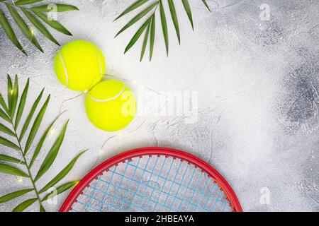 Tennis.Composition sportive avec balles de tennis avec une raquette et des feuilles de palmier sur fond bleu avec espace de copie.Le sport et un mode de vie sain.La conce Banque D'Images