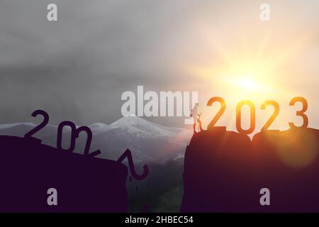 Année de chargement de 2022 à 2023.Silhouette homme de sport sur le ciel de coucher de soleil au sommet de la montagne résumé arrière-plan.Bonne année et fête conc Banque D'Images