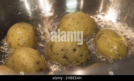 Gros plan pour les pommes de terre brunes mijotées dans l'eau bouillante dans la casserole, nourriture et cuisson des légumes concept.Les pommes de terre étant cuites dans une eau chaude bouillante Banque D'Images