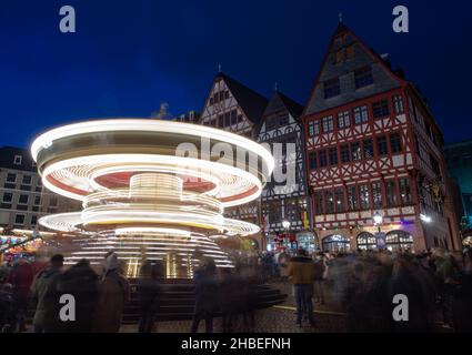 19 décembre 2021, Hessen, Francfort-sur-le-main : des visiteurs surpeuplés se tiennent au carrousel pour enfants au marché de Noël sur le Römerberg à Francfort-sur-le-main (photo en exposition longue).Alors que dans beaucoup d'autres endroits à Hesse, les marchés traditionnels ont été annulés en raison de la pandémie de Corona, le marché de Francfort a été autorisé à se dérouler sous certaines conditions. Banque D'Images