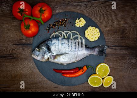 Mahi-mahi ou la ligne de poissons dorado, vue de dessus.sur le plan de coupe noir et une table en bois. Banque D'Images