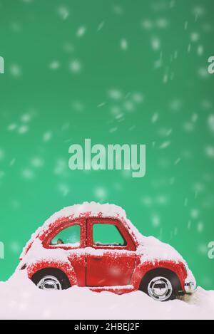 Gros plan d'une voiture miniature sur fond vert mat et neige couverte. Banque D'Images