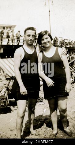 Une photographie vintage d'un jeune couple debout sur la plage portant 1920s maillots de bain similaires. Banque D'Images