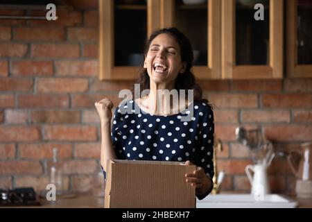 Émotionnellement heureux jeune hispanique femme déballage énorme boîte en carton. Banque D'Images