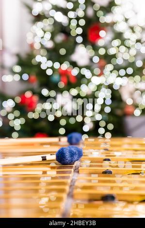 Bâtons de vibraphone reposant sur cet instrument à percussion.En arrière-plan, les lumières floues et floues de l'arbre de Noël. Banque D'Images