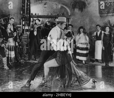 Espagnol Homme et femme dansant à l'intérieur au club ou au restaurant avec des gens rassemblés autour d'observer.Vers 1920 Banque D'Images