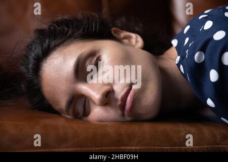 Une jeune femme hispanique exténuée couché sur un canapé confortable. Banque D'Images
