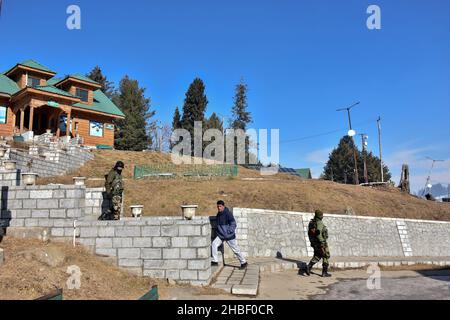 Gulmarg, Inde.19th décembre 2021.Un homme marche à l'étage tandis que les troopers paramilitaires patrouillent pendant une journée froide d'hiver dans une célèbre station de ski de Gulmarg, à environ 55kms de Srinagar.Crédit : SOPA Images Limited/Alamy Live News Banque D'Images