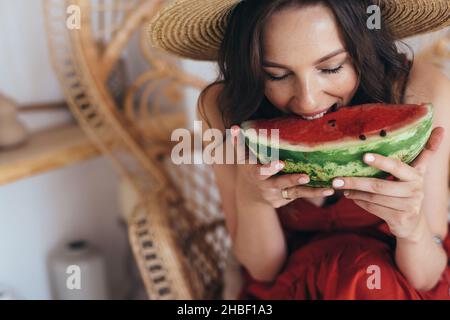 La jeune femme mange un gros morceau de pastèque. Banque D'Images