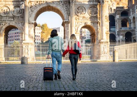 Jeune couple en voyage à Rome.Le jeune couple marche et tient les mains.L'homme traîne son chariot. Banque D'Images