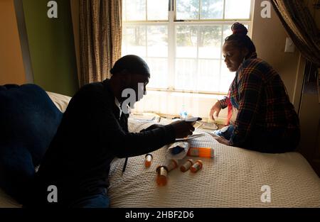 Smyrna, Géorgie, États-Unis.19th décembre 2021.Genetra Quick aide son mari Robert à trier ses médicaments dans l'hôtel de séjour prolongé près d'Atlanta où ils vivent avec trois filles du collège.« ItÃs tout ce que nous pouvons nous permettre, » et nous sommes suspendus par de minces fils et prières », a déclaré Quick, 36, qui livre des repas aux clients Uber Eat, travaillant 14-16 heures par jour.Son mari a reçu un diagnostic de pancréatite sévère et d'autres problèmes abdominaux qui limitent sa capacité à travailler.« il reste avec les filles pendant que je travaille », a-t-elle dit.La famille est au bord de l'itinérance, survit au quotidien dans le Banque D'Images