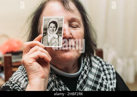 Femme âgée tenant une photo en noir et blanc de son jeune soi.Concept de passage du temps Banque D'Images