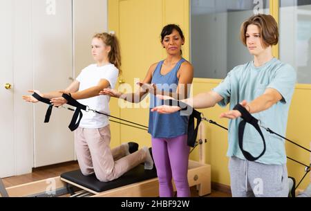 Adolescents d'entraînement pilates dans la salle de gym avec entraîneur Banque D'Images