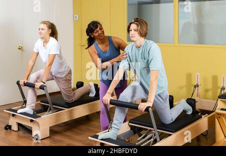 Adolescents d'entraînement pilates dans la salle de gym avec entraîneur Banque D'Images